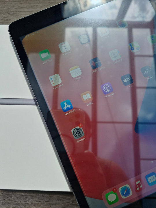 Apple iPad 7 32GB Wifi Space Grey - New Battery (Imperfect) Close-up of a tablet screen with app icons on a stand.