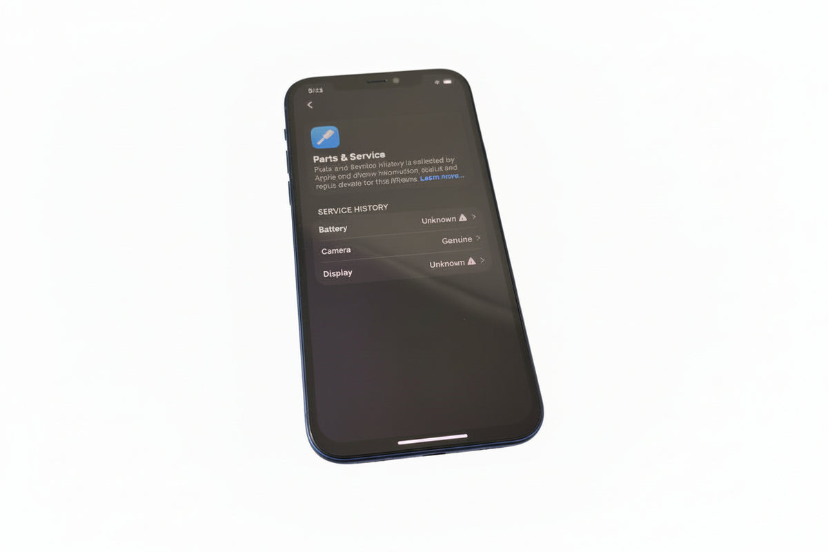 Black smartphone on a bubble wrap pad on a blue surface with a keyboard and earphones.