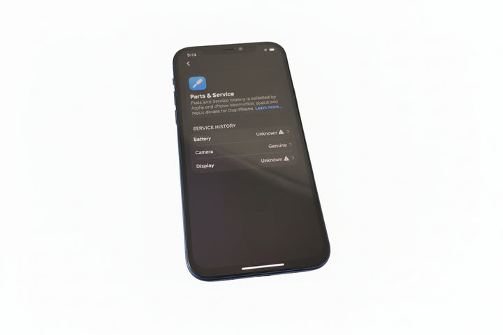 Black smartphone on a bubble wrap pad on a blue surface with a keyboard and earphones.